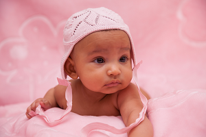 African American baby girl on pink blanket with pink crocheted hat.